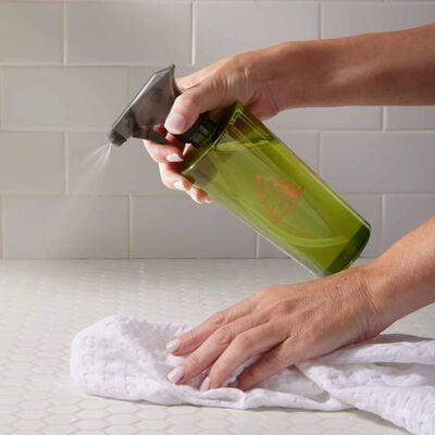 Holding Towel and Spraying Counter with Thymes Frasier Fir All-Purpose Cleaning Spray